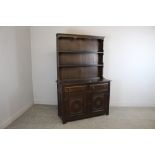 A modern dark-stained elm dresser, of traditional form, the panelled cupboard doors with carved