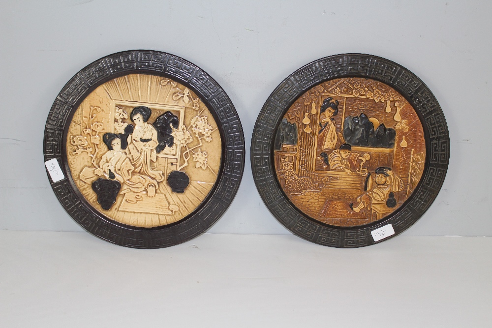 A pair of Bretby pottery circular wall plaques, relief moulded with traditional Japanese figural