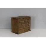 A miniature pine chest of four drawers 32cm x 39cm x 23cm cut-out section to top (back edge)