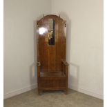 A 1930's Art Deco oak hall stand, the arched back with oblong mirror, embossed decoration and an