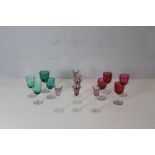 A selection of coloured wine glasses, four cranberry tined, four green tinted and six amethyst