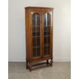 An early 20th century glazed oak bookcase with scroll carved frieze over arched lead glazed doors