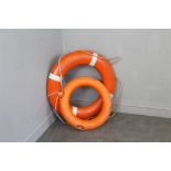 Two orange plastic life preservers/bouys, the largest 74cm dia