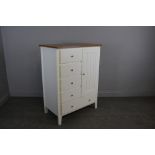 A modern tall boy chest of drawers, four short drawers, cupboard section and long base drawer