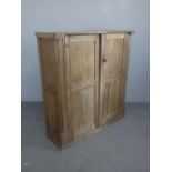 An antique pine two-door cupboard, with panelled doors and ends, 134cm x 125cm x 43cm damage to