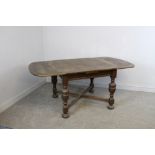 An oak draw-leaf table, with rounded rectangular top and turned cup and cover supports linked by