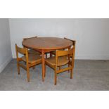 A 1970's teak effect circular extending dining table and four chairs 73cm x 113cm