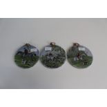 A group of three Upsala Ekeby (Sweden) hunting scene roundals, pierced with leather hanging.15cm