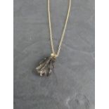 A smoky quartz pendant with small white stone set surmount, suspended by a fine yellow metal chain