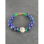 A Lapis Lazuli and emerald bead bracelet with central white metal cat-mask bead and gilt metal clasp