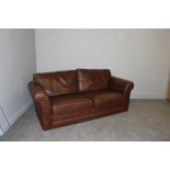 A large brown leather three-seater settee 90cm x 210cm x 95cm