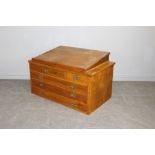 A mid-century stained pine plan chest with large writing slope to top 79cm x 129cm x 73cm