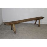 A 19th century elm bench or form, with rounded oblong top and four simple supports 40cm x 197cm x