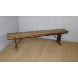 A vintage pine village hall bench or form, with iron supports to the trestle ends 45cm x 182cm x