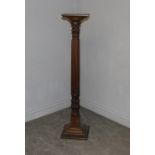 A mahogany torchere, the square top over a moulded circular collar and boldly reeded column with
