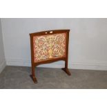 A mahogany firescreen, with slightly arched top rail over the embroidered silk-work panel of