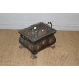 An Arts and Crafts copper log or coal box, the hinged and embossed architectural top over a bombe