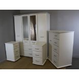 A modern white laminate four piece bedroom suite, comprising a wardrobe, tall-boy chest and two