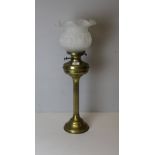 A brass column oil lamp, having a moulded and frosted glass shade over the burner with twin