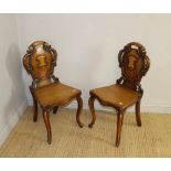 A pair of Victorian oak hall chairs, having scrolled shield backs above serpentine fronted solid