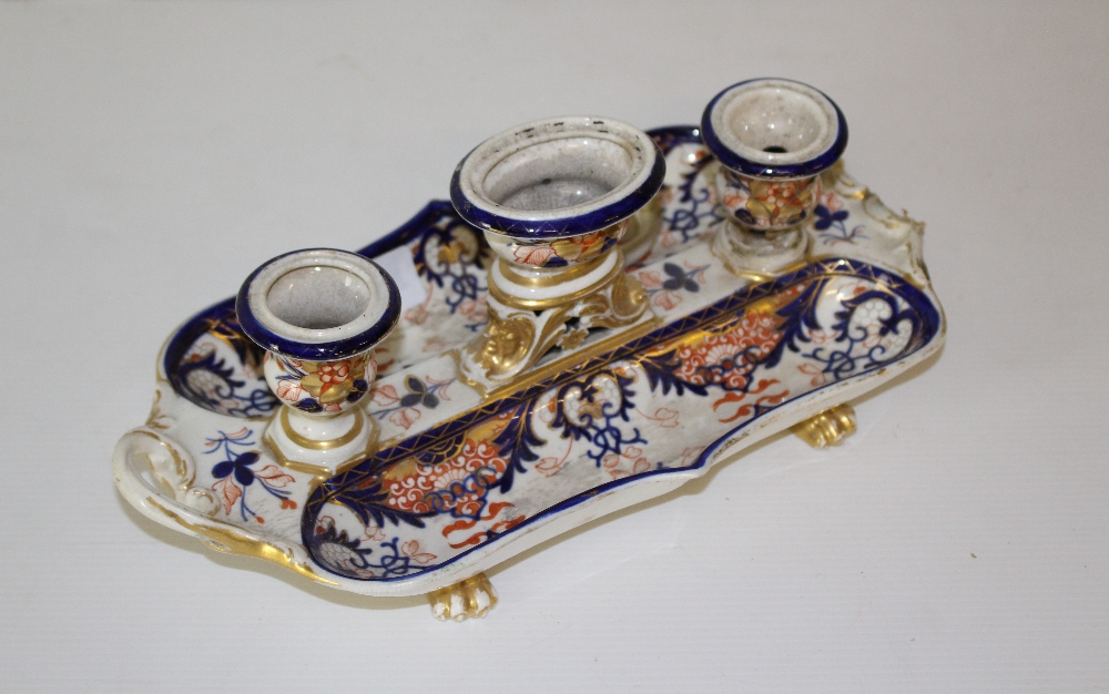 An early 19th century Derby porcelain inkstand, having three central urn-form wells flanked by