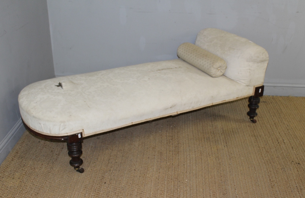 A Victorian mahogany framed chaise longue or day bed, with sprung seat and padded back raised on