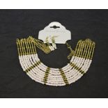 A costume jewellery necklace and earring set, of African design with yellow metal and pearl style