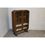 A 1940's glazed oak display cabinet, the doors with ghaped glazing bars and moulded decoration