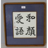 A framed Chinese four character text, within a blue card mount and rounded square frame, under glass