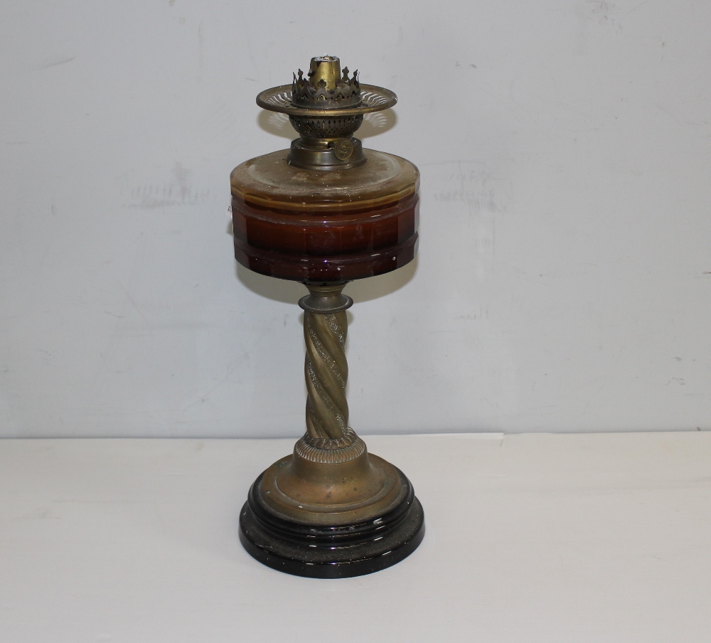 A Victorian brass and glass oil lamp, with brass burner over the amber glass reservoir and barley-