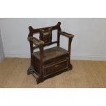 An Arts and Crafts style oak hall seat, the shaped and pierced back with central panel bearing a
