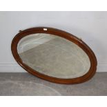 A large early 20th century oval mahogany framed mirror, with bevelled plate, makers label verso C.