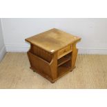 An oak magazine table, the square top above a single drawer and shelving, flanked by divisions for