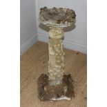 A cast composite stone bird bath/table the small dished and shaped square top over a fluted column