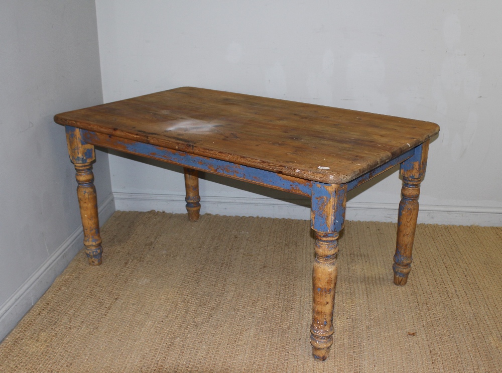 A modern pine farmhouse kitchen table, the rounded rectangular top raised on a blue painted base