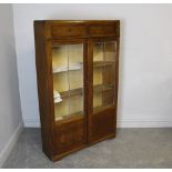 A 1930's oak display cabinet, having two drawers over glazed and panelled doors, enclosing