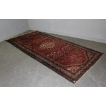 An 'Oriental carpet' of Persian design with central lozenge and foliate field within spandrels and