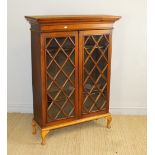 A mahogany display cabinet, with moulded surmount over geometrically glazed doors, enclosing