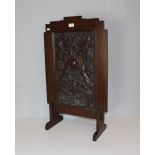 A carved oak firescreen, the rectangular panel carved in relief and stippled with ornate foliate