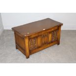 A reproduction oak three panelled coffer, the hunged rectangular top above a central linen-fold