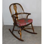 A reproduction elm Windsor rocking chair in the 18th century style, the arched back with central