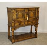 A reproduction oak court cupboard, with carved and arched panelled doors between foliate carved