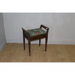 An Edwardian mahogany piano stool, with hinged seat and out-swept handles over tapering square