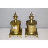 A pair of brass table tobacco jars, the spreading circular finial topped covers above the