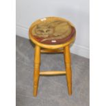 A modern beech four legged stool, the dished circular top painted with a resting cat, raised on four