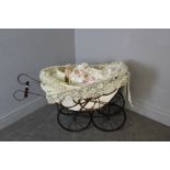 A metal and wicker doll's pram containing a modern Alberon bisque headed doll 60cm x 93cm some