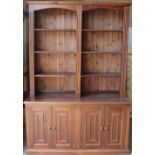 A large modern dark stained pine bookcase over cupboards, the moulded cornice above two arched
