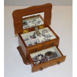 A small wooden jewellery box containing various silver and white metal jewellery, including an Ingot