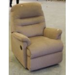 A reclining armchair, in brown material with repeating lozenge design, used condition but