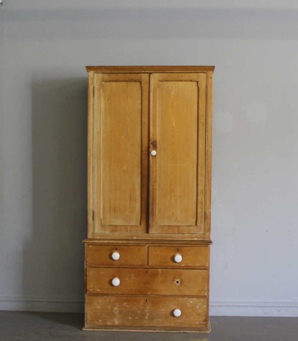 A Victorian pine cupboard over chest, the short plain cornice over two long panelled doors opening
